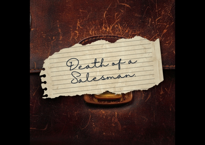 death of a salesman handwritten on a torn piece of paper sitting on an old brown leather briefcase