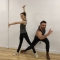 A female dancer with one arm up and one arm outstretched and a male dancer lunging forward with his arm outstretched.