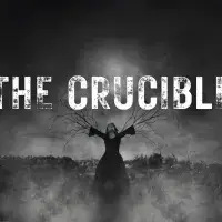 Black and white image of a girl on a stake with branches growing out of her arms. Smoke and dark lighting with The Crucible in rough looking letters